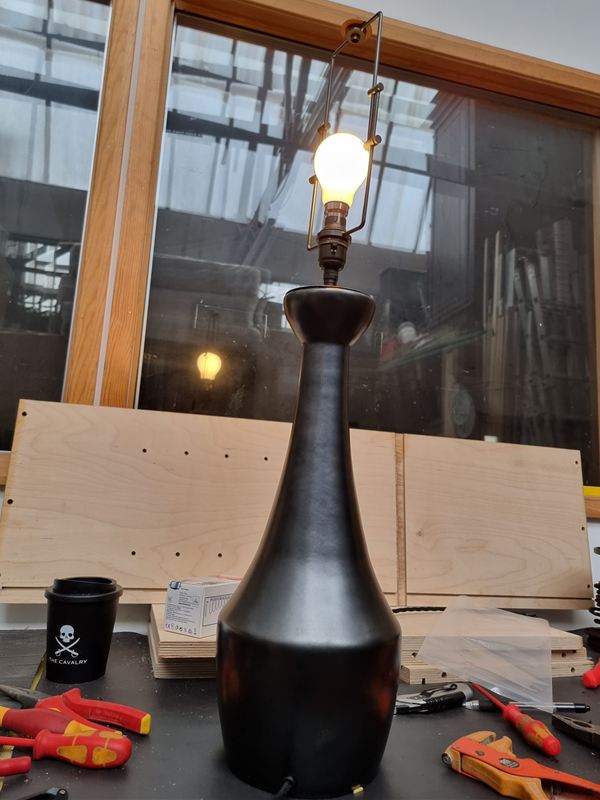 Tall black ceramic table lamp, switched on