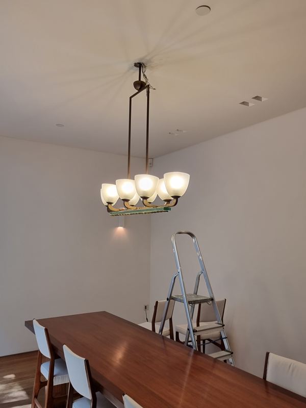 Six-light chandelier with frosted glass shades, lit above a dining table