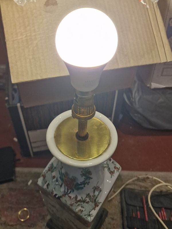 Painted porcelain lamp with a brass top plate, switched on